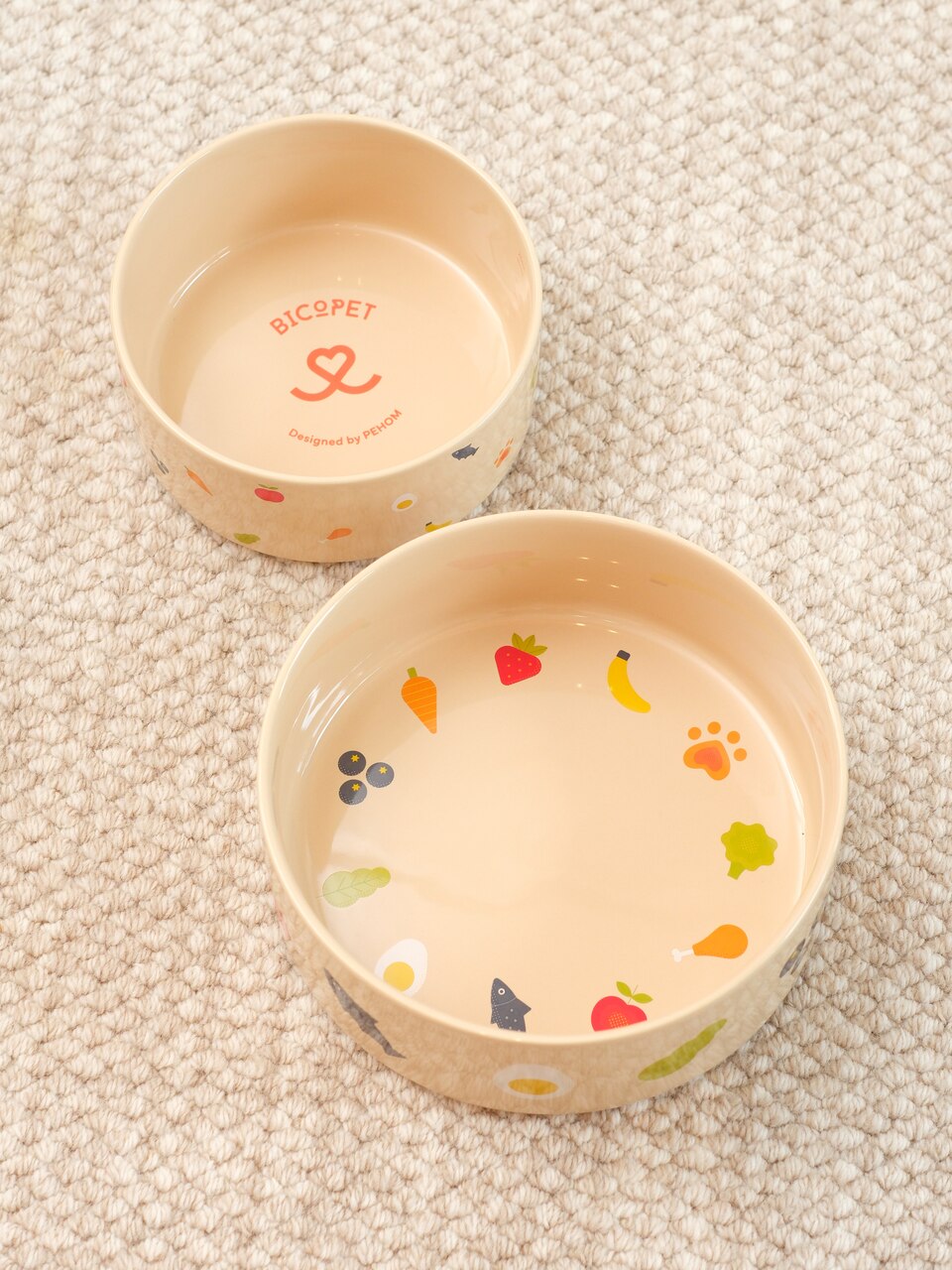 Two ceramic pet bowls with colorful designs on a textured surface