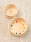 Two ceramic pet bowls with colorful designs on a textured surface