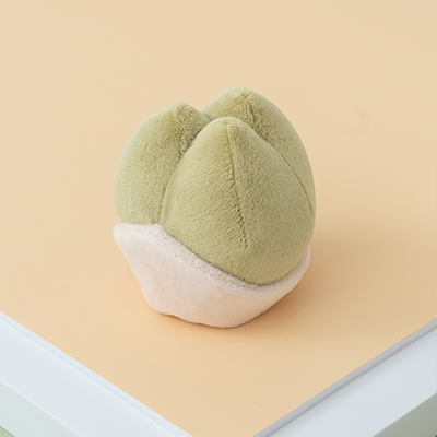 Green plush toy resembling a cloud on a beige surface with a white base.