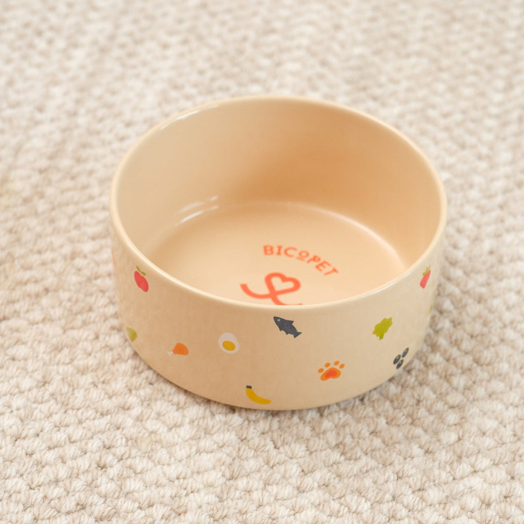 Beige pet bowl with colorful designs on a beige carpet