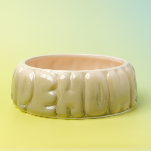 Beige ceramic bowl with embossed text on a gradient yellow background