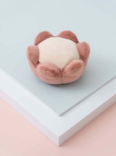 Flower-shaped plush toy on a light blue surface with a pink base