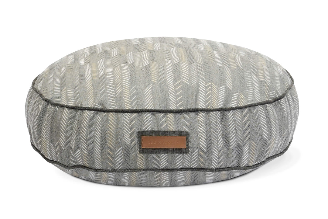 Round gray patterned pet bed with a brown label on a white background