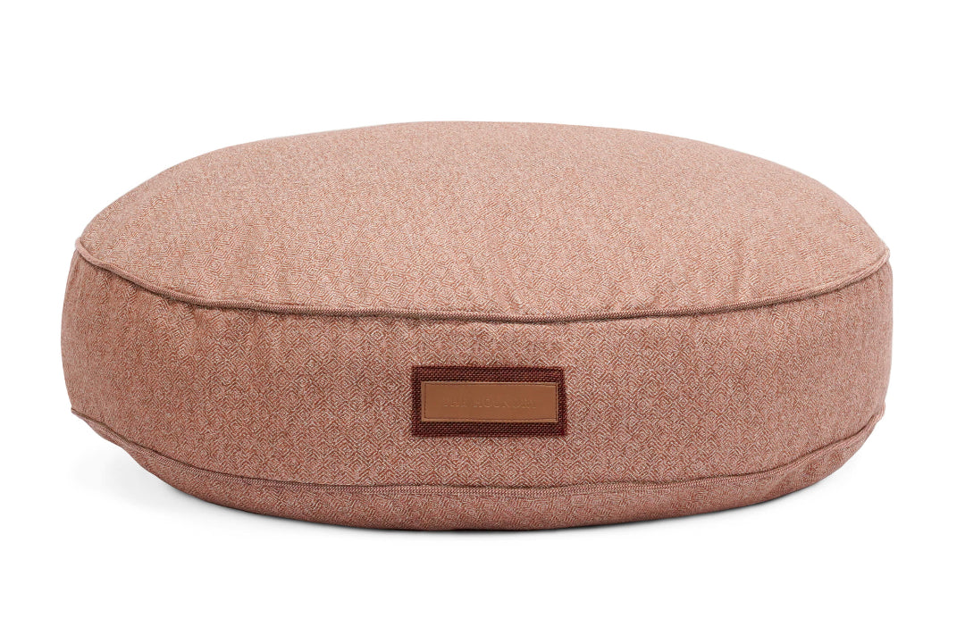 Round pink cushion with a leather label on a white background