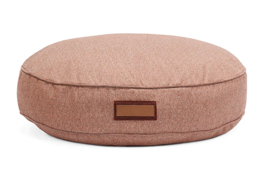 Round pink cushion with a leather label on a white background